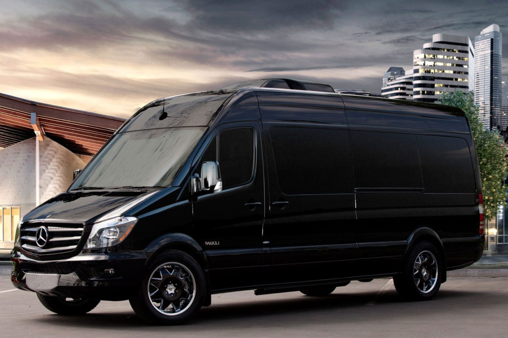 Chauffeur beside a black Mercedes Sprinter van