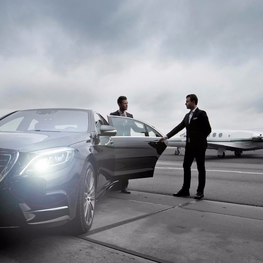 Chauffeur opening the rear door of a black car