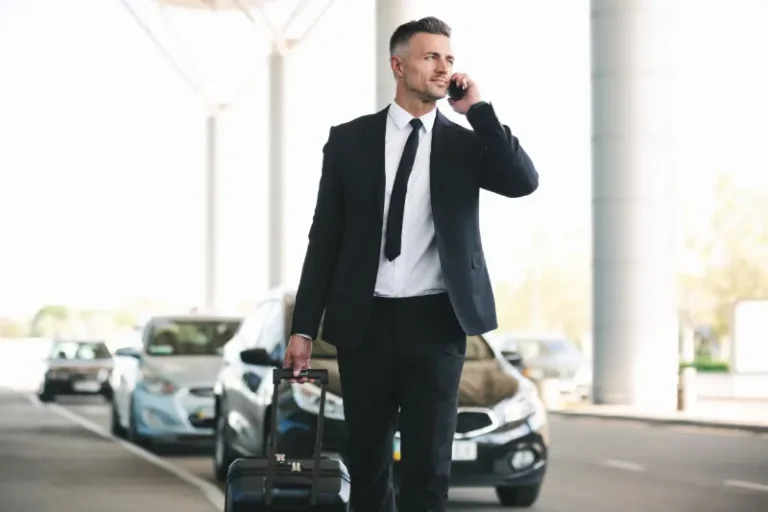Business traveller on the phone walking with his luggage