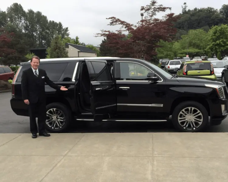 Chauffeur waiting beside a black Cadillac Escalade