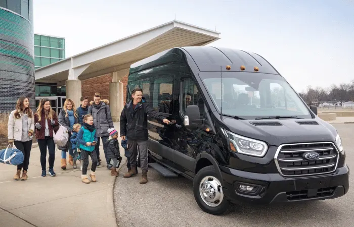 Passengers with luggage beside a Ford Transit van at a terminal