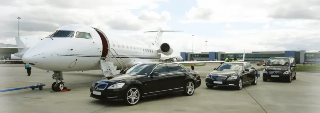 Black Mercedes sedans waiting beside a private jet