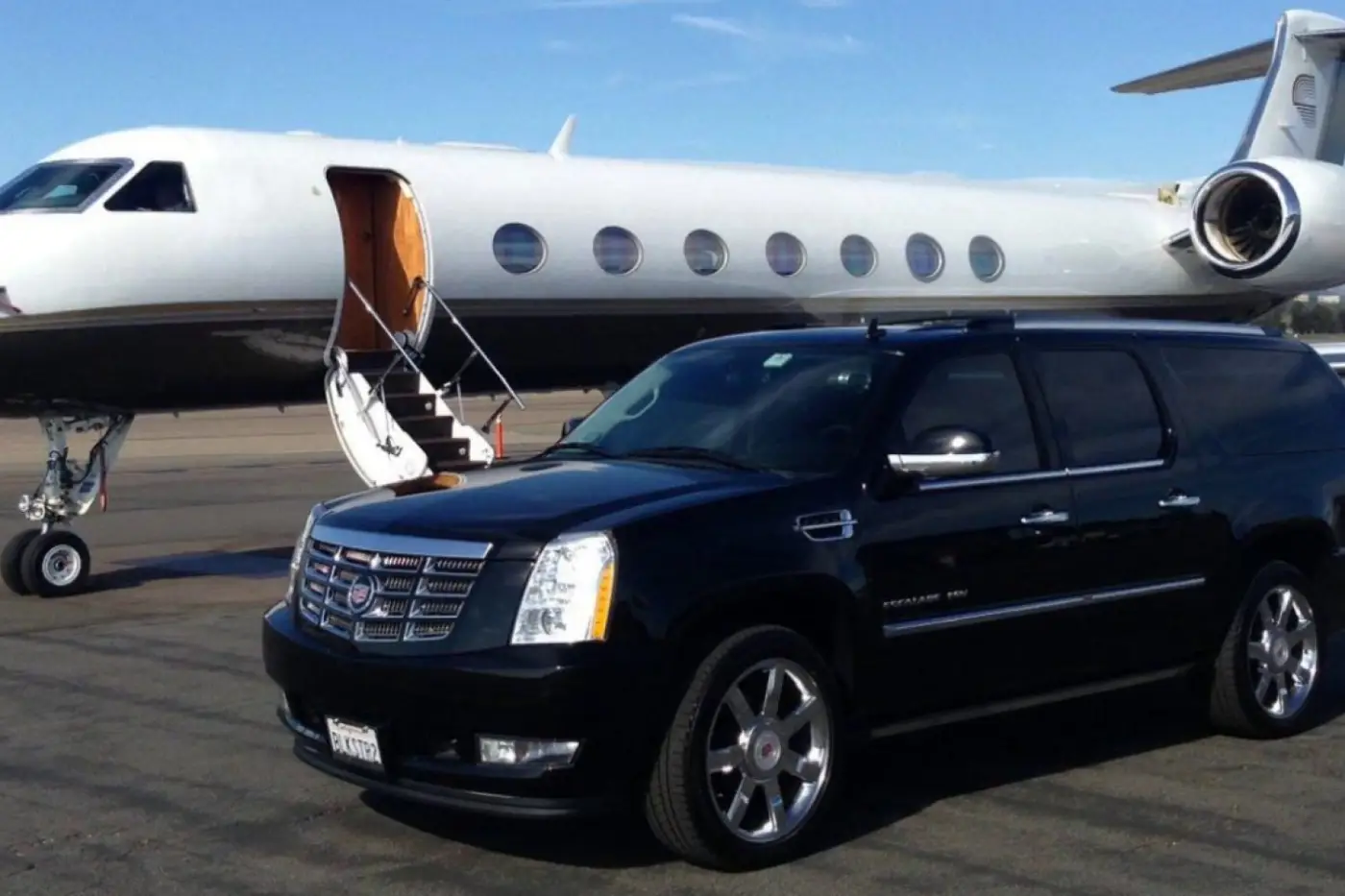 Black Cadillac Escalade parked beside a private jet