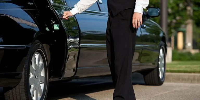 Chauffeur holding the rear door of a black sedan