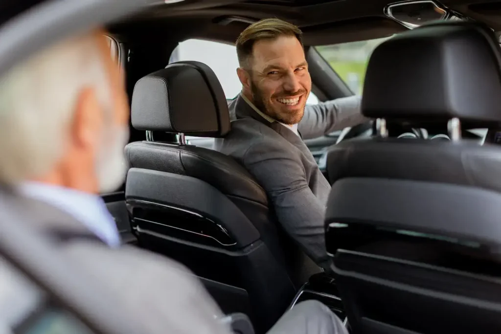 Business traveller smiling in the back seat of a chauffeured car