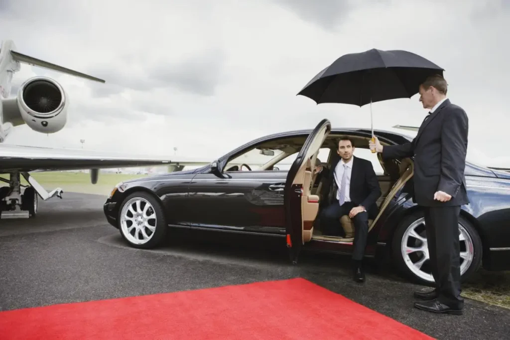 Chauffeur holding an umbrella for a passenger stepping out beside a private jet