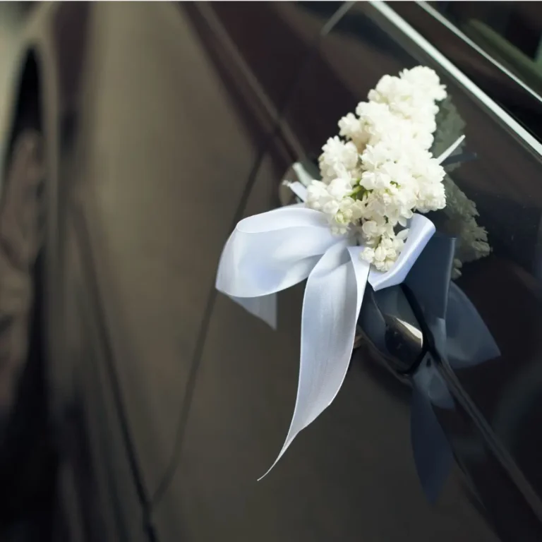 White wedding flowers tied to the door of a black car