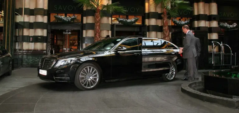 Chauffeur beside a black Mercedes at a hotel entrance